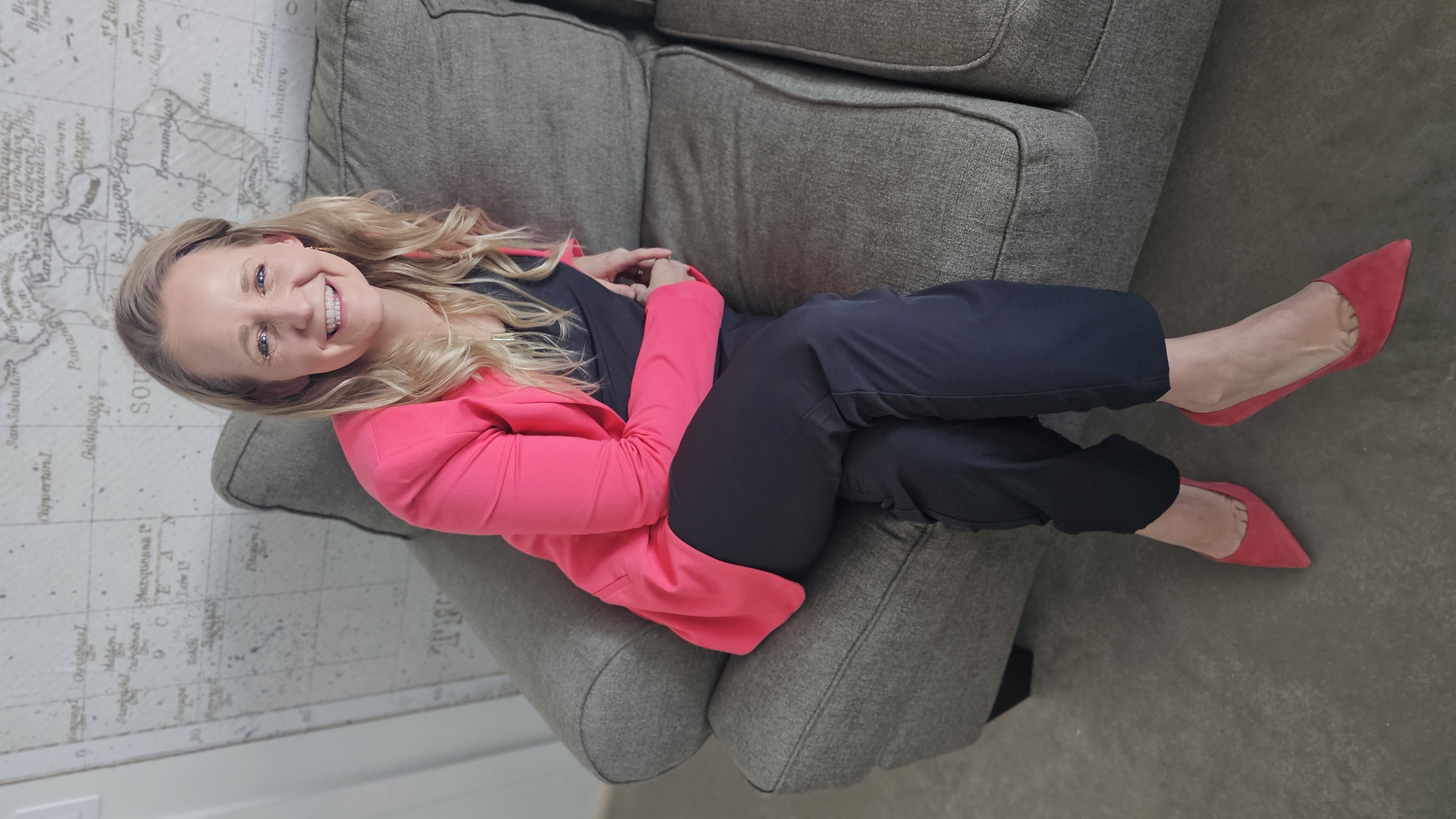 Toni Schafer in a professional setting, seated in front of a world map, representing her global real estate education mission